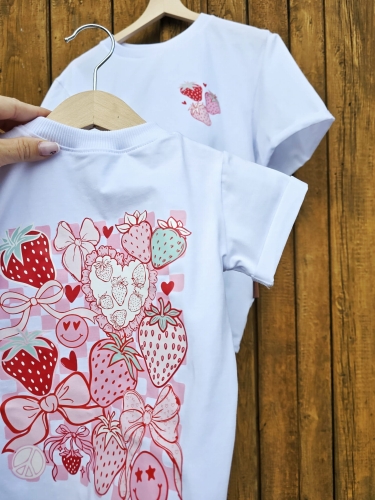 Dziewczęca bluzka z nadrukiem truskawek na tle drewnianej ściany